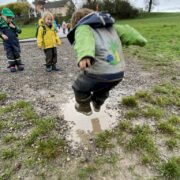 naturspielwald_waldspielgruppe_regenwetter_kind_hüpft_pfütze_schlamm